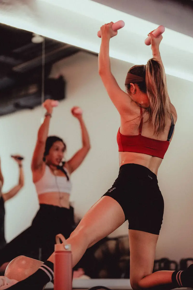Two women lifting dumbbells overhead