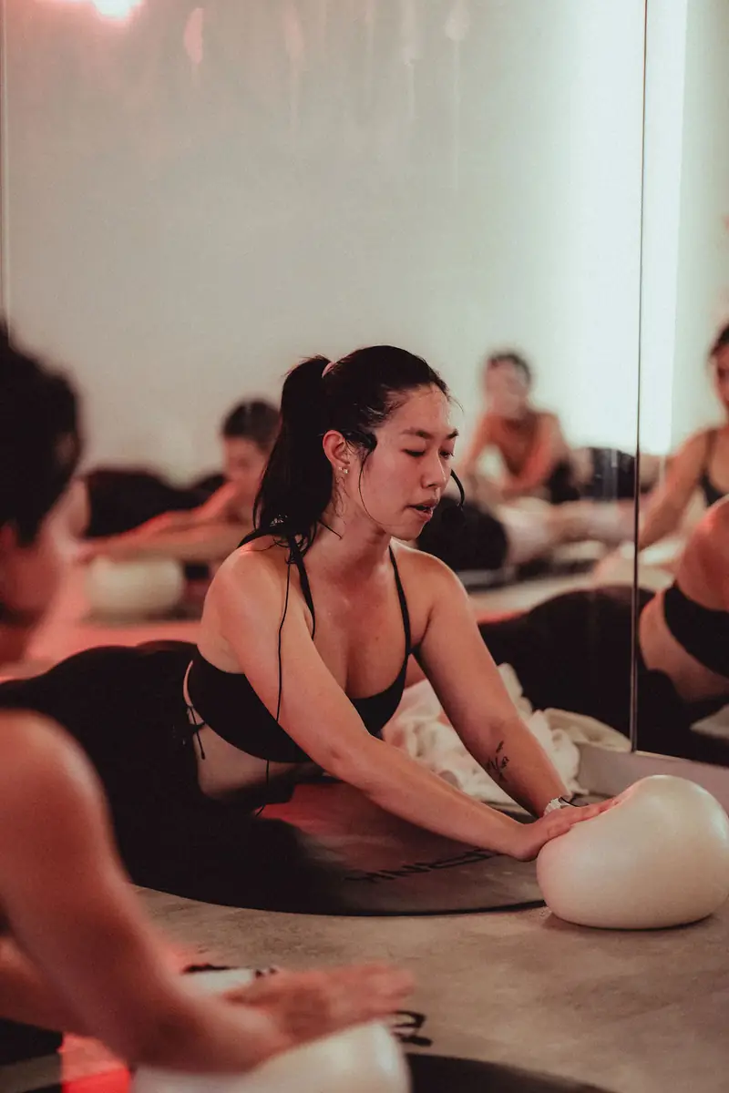 A woman stretching on her mat with a pilates ball