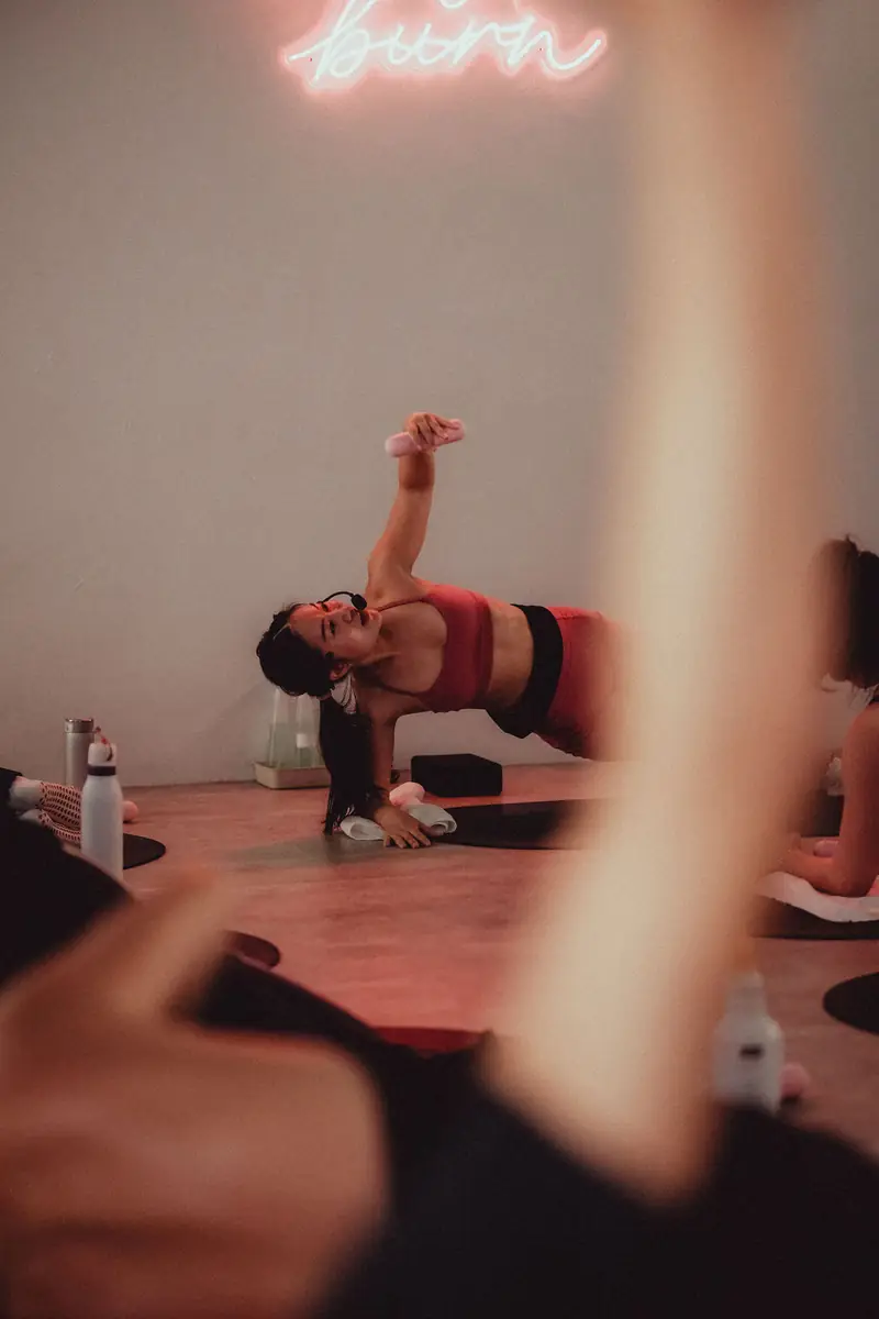 A side plank on the mat under a pink neon sign
