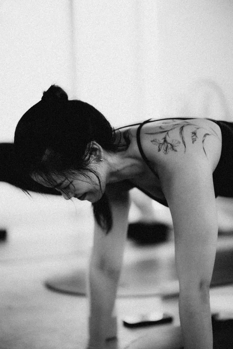 Black and white photo of a woman bending over her mat