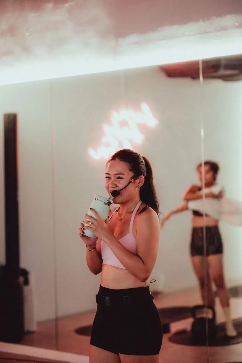 A hot mat instructor with a headset, drinking water