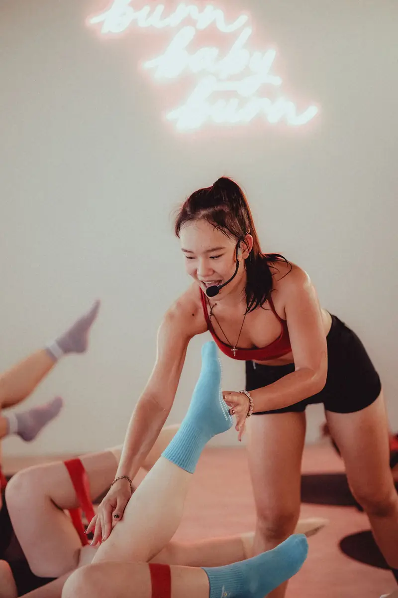 An instructor with a headset helping a client work with a resistance band
