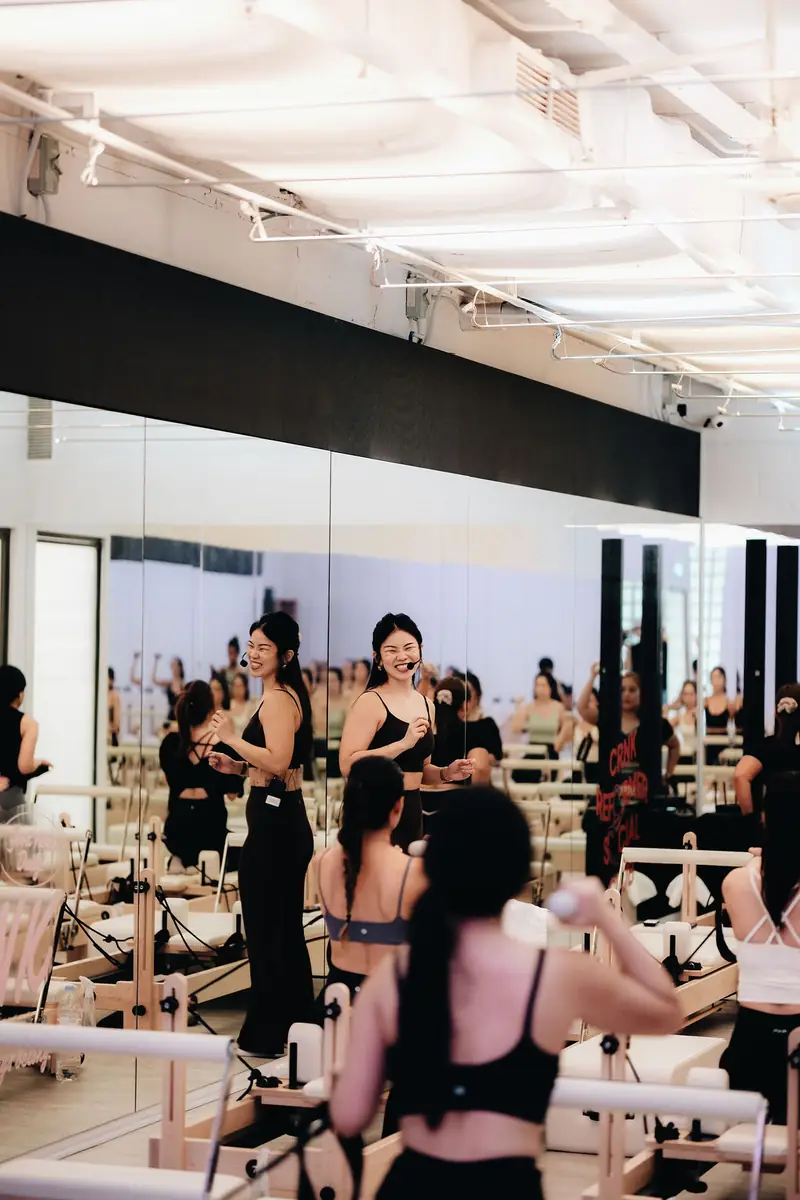 A bright Reformer Pilates room, the instructor leading from the front