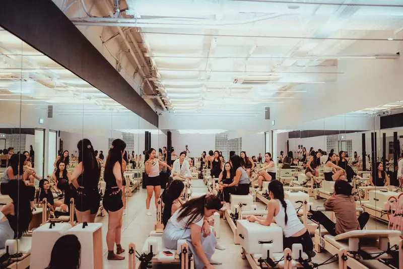 A full reformer pilates room seen wide, with rows of reformers