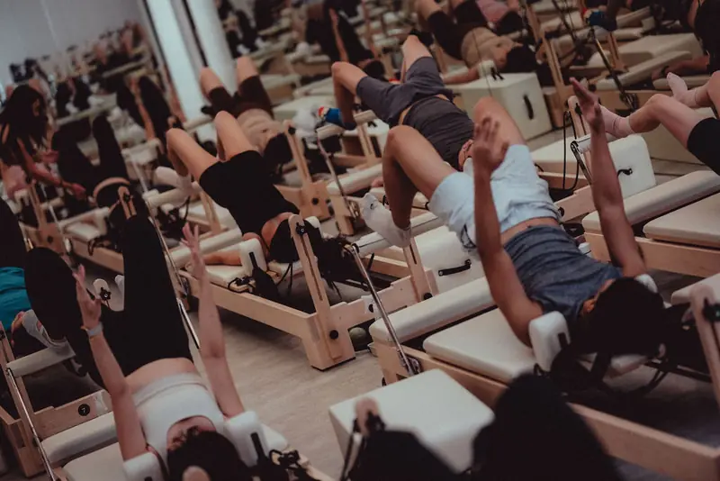 A class on reformers with their legs in the straps