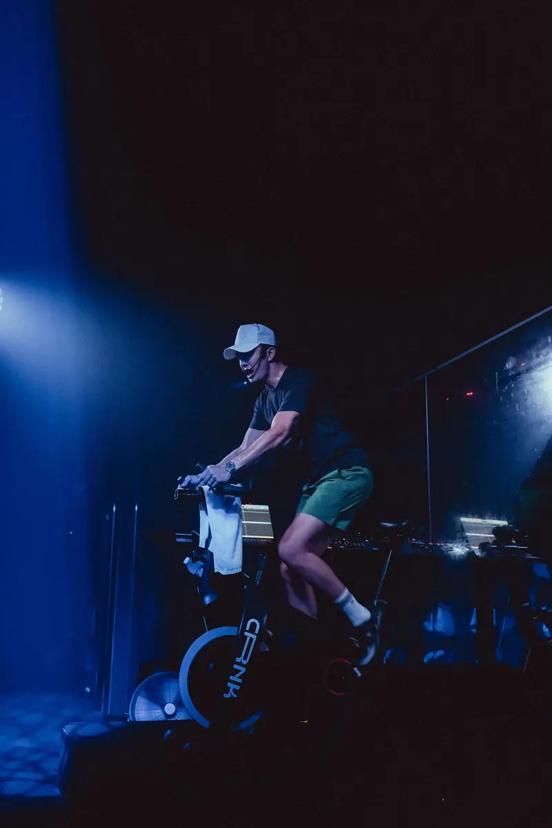 A rider in a white cap on the bike in blue light