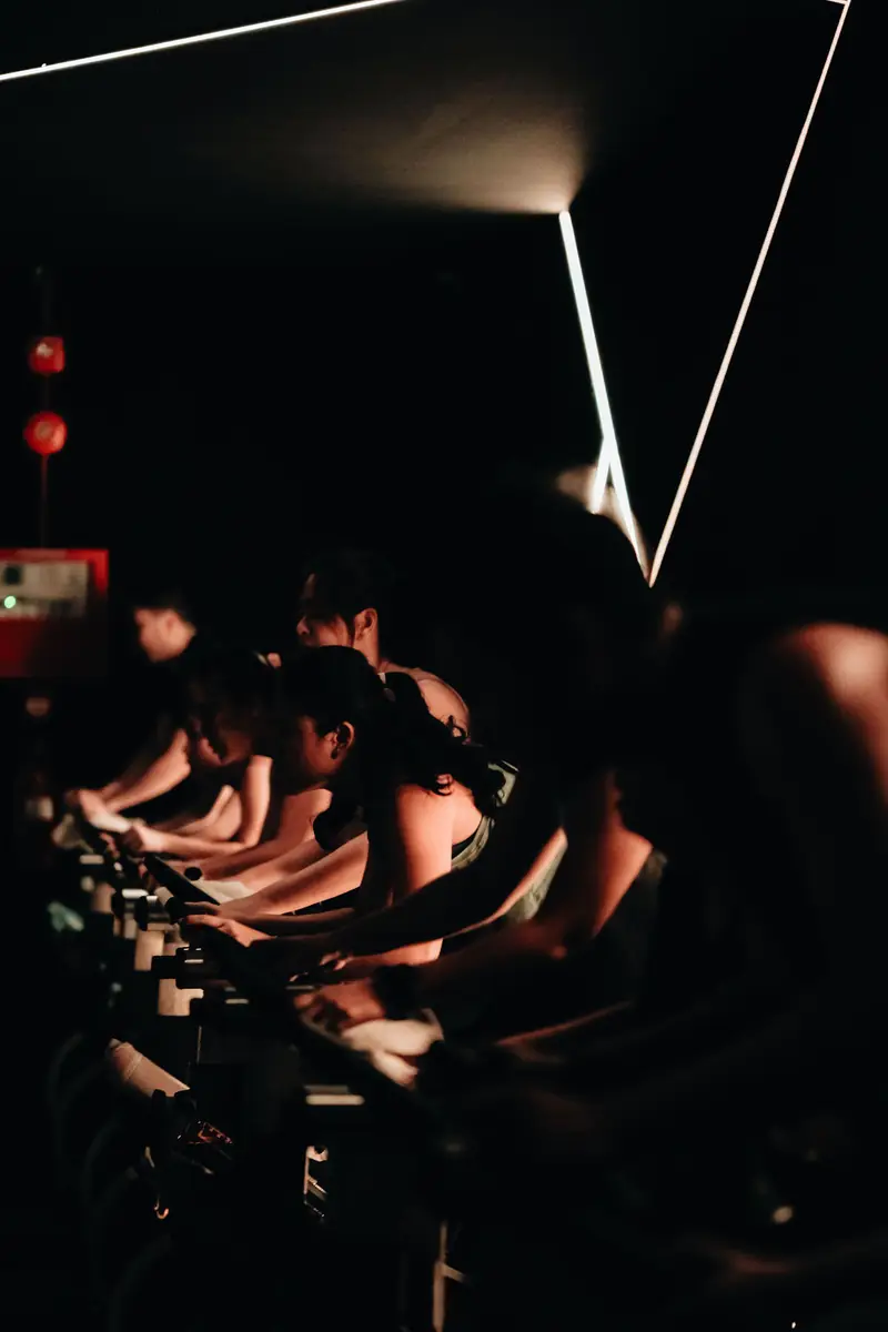 Riders in shadow under a neon line light