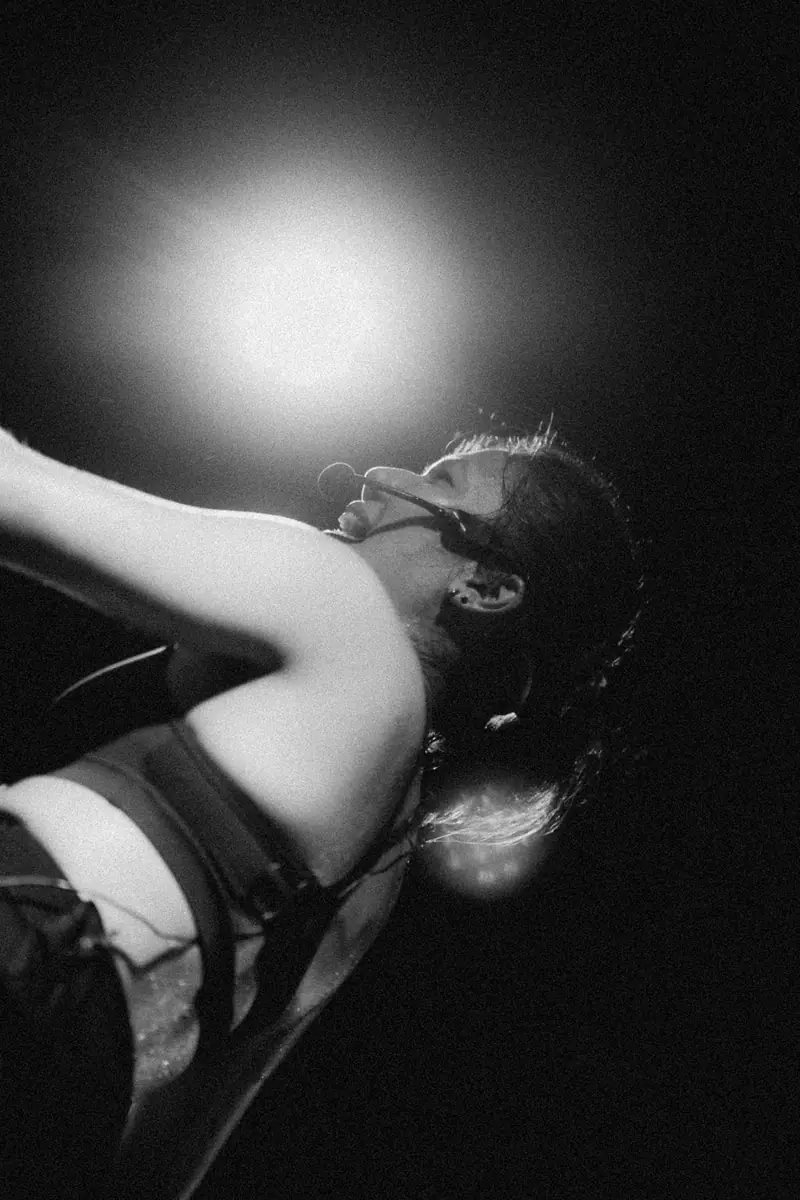 Black and white photo of a rider looking up into a spotlight