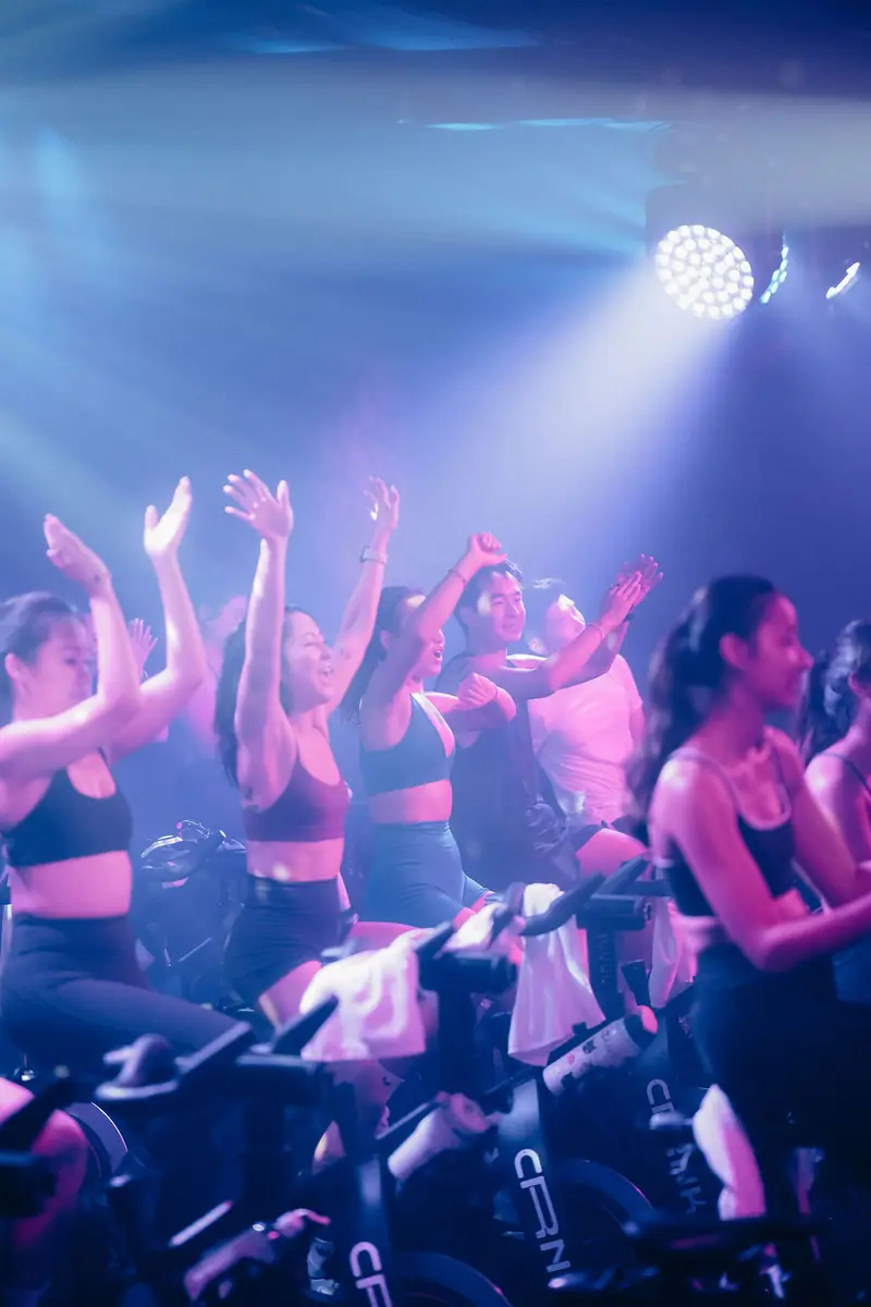 Riders with their hands up under blue and pink stage light