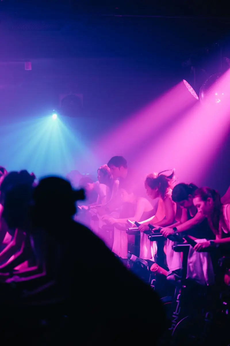 Pink and blue light beams over a room of riders