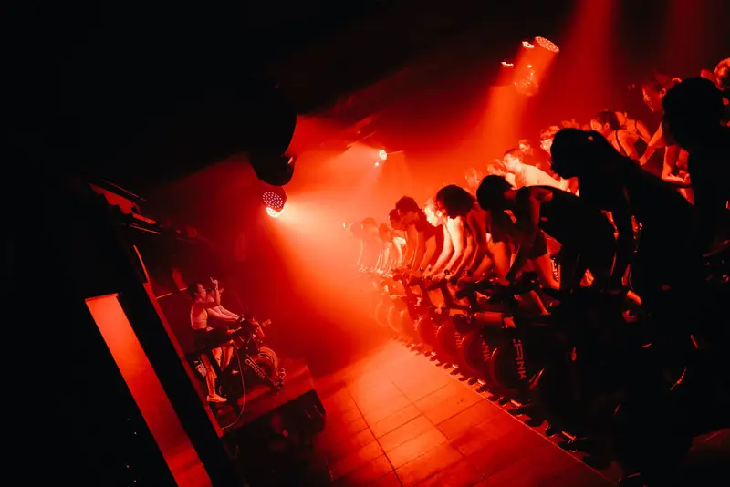 Rows of riders in a red-lit room