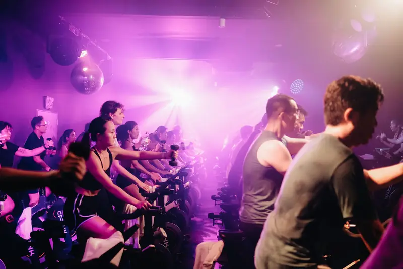 Riders smiling mid-class under purple lights