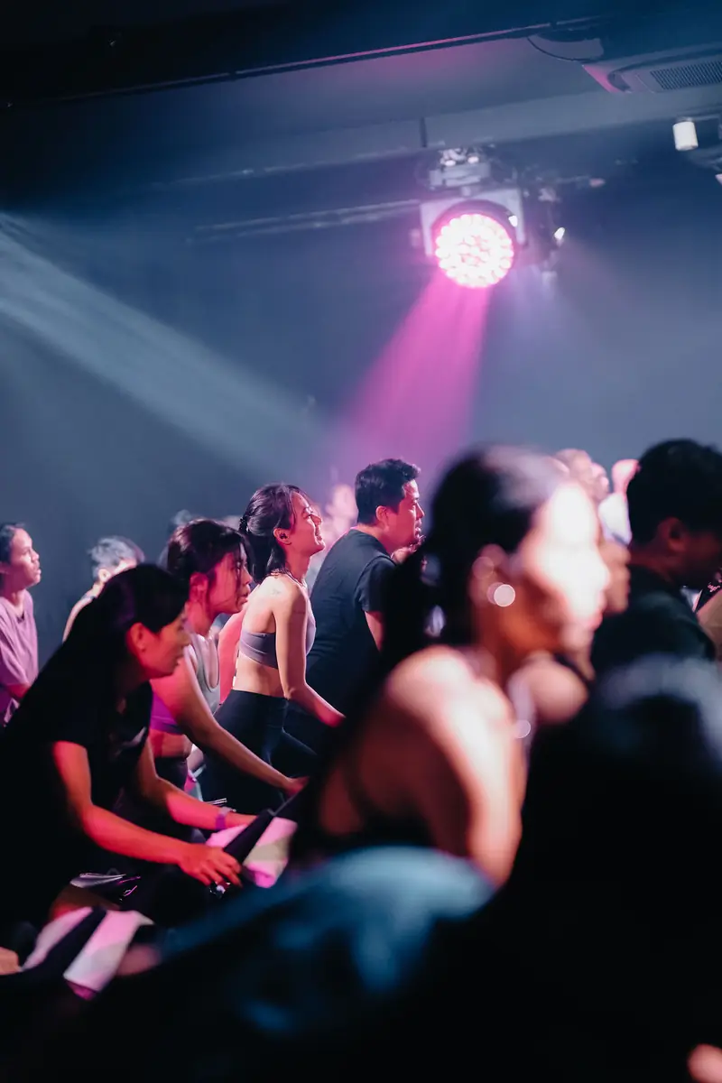 A crowd of riders under a pink spotlight