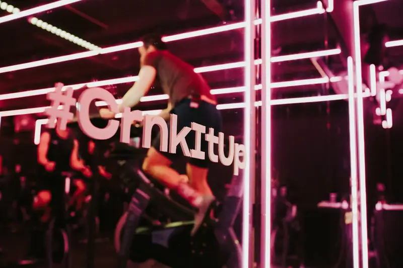 A rider on the bike behind the neon #CrnkItUp sign